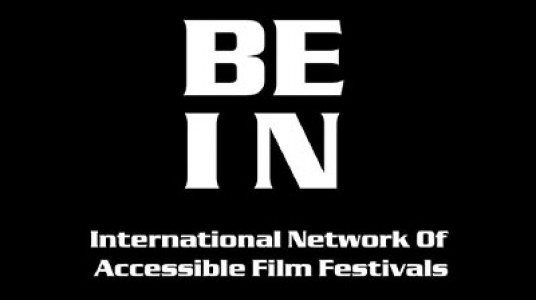 It is written BE IN in two lines on a black background in big white letters. Just below it, in two lines, in smaller fonts, International Network Of Accessible Film Festivals is written.