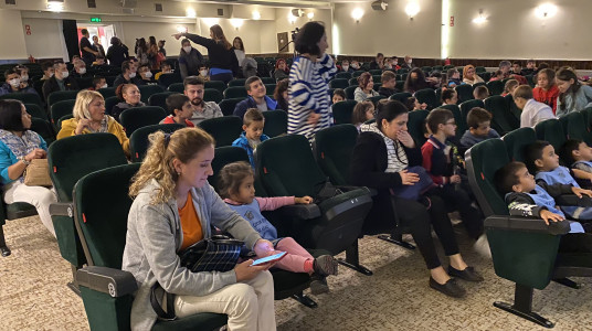 Görselde, Yunus Emre Kültür Merkezi'nin gösterim salonunda koltuklarında çocuklarıyla birlikte oturan anne ve babalar görülüyor.